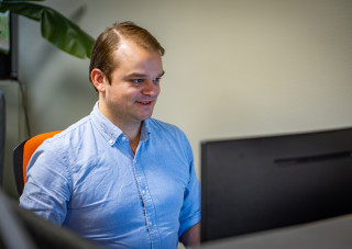 Deux collègues discutent et sourient dans un espace de travail moderne, devant un comptoir lumineux.