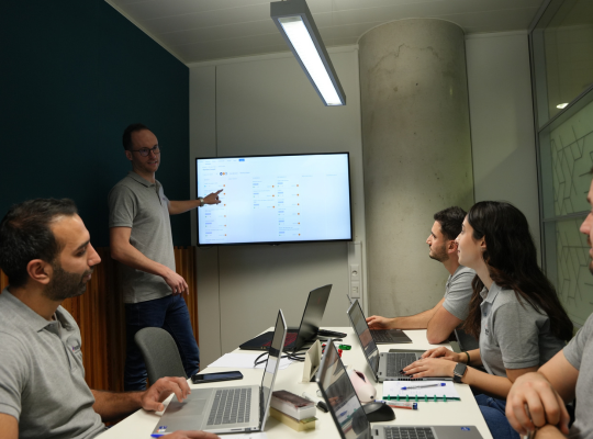 Équipe en réunion collaborative avec des ordinateurs portables et un tableau interactif